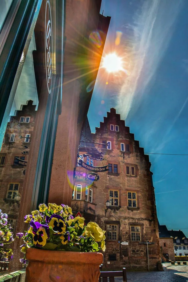Café Hexenstübchen mit Blumen und Sonne vor historischer Kulisse