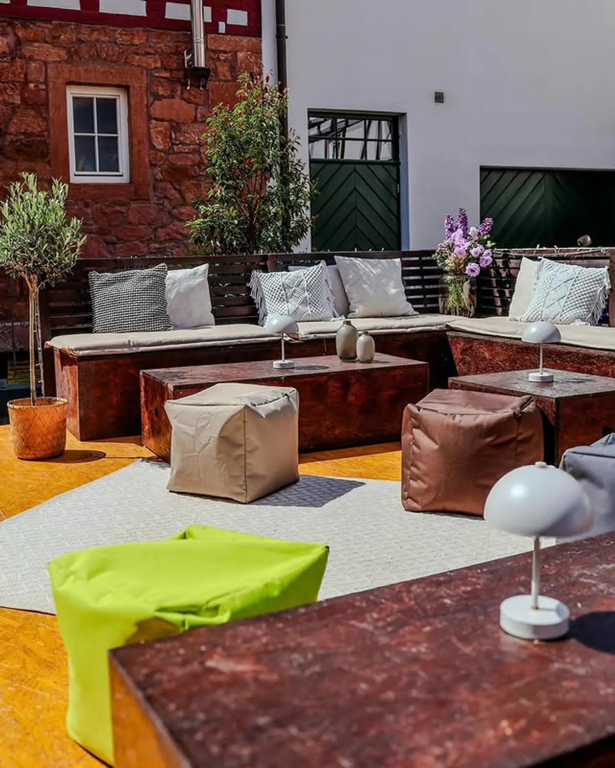 Sonnige Innenhof-Lounge mit Sitzkissen vor Sandsteinfassade