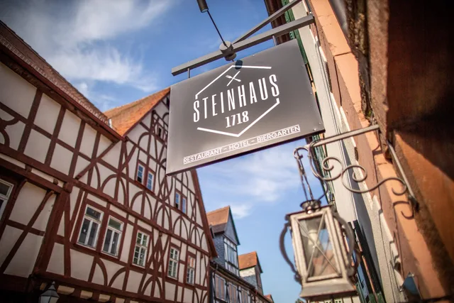 Steinhaus 1718 Schild vor Fachwerkkulisse in der Büdinger Altstadt