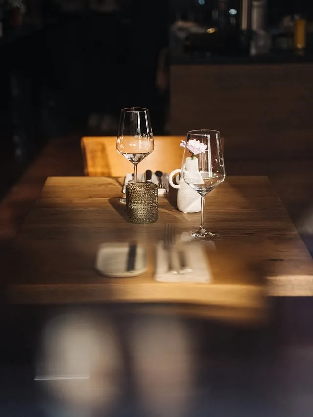 Tisch mit Weingläsern und Kerze im Lichtstreif